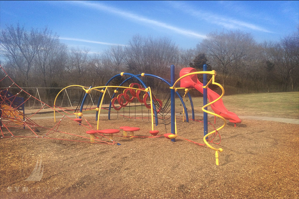 before image of hazel grove elementary playground with a red slide on top of wood mulch