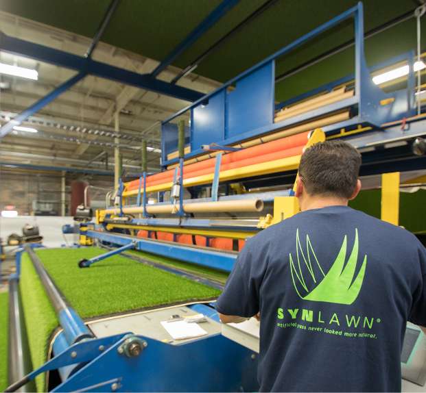 Turf_Manufacturing_1 Man with synlawn shirt watching turf go through a roller