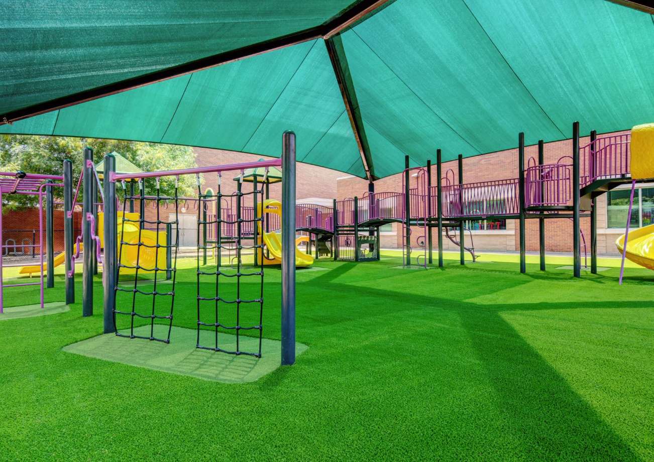 Trampoline_Surfacing Playground surfacing of artificial grass with a green canopy providing shade