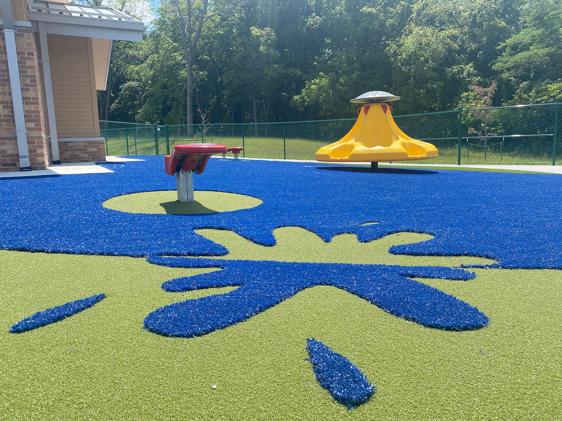 Kansas City Playground (4) Closeup of a playground surfacing with a design and blue and green turf