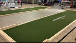 Indoor Bocce ball court with white text on the turf
